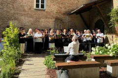 Der Chor singt im Innenhof, Alfons Brandl dirigiert am Klavier
